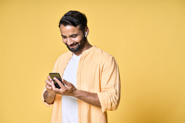 Happy smiling indian ethnic man wearing earbuds using smartphone looking at cell phone watching...
