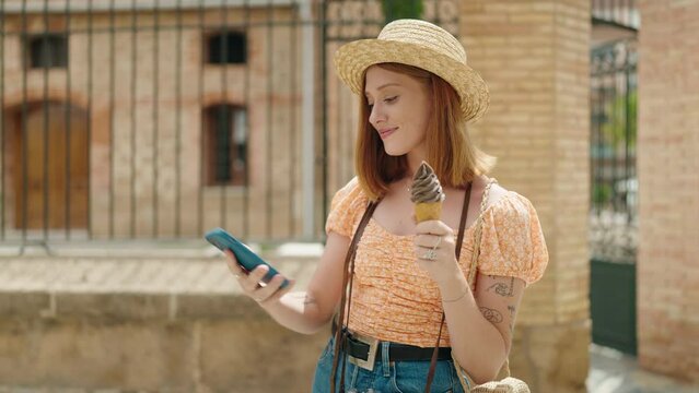 Young redhead woman tourist make selfie by smartphone eating ice cream at street