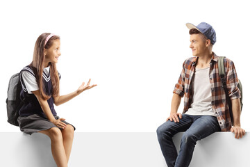 Schoolgirl and a teenage student sitting on a blank board and talking