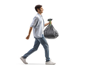 Full length profile shot of a casual man walking and carrying a plastic bag