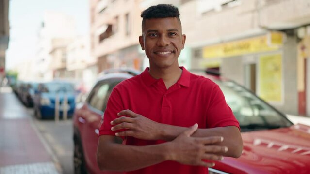 Young latin man smiling confident standing with arms crossed gesture at street