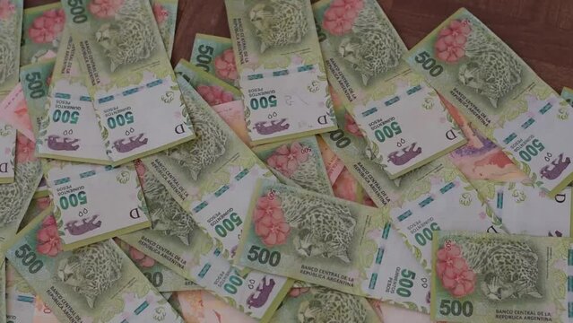 Fajo de billetes de pesos argentinos cae sobre un colchon de billetes, billetes de 500 pesos argentinos
