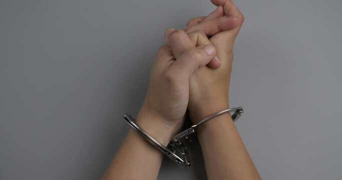 deprivation of liberty hands in handcuffs on gray table, arrest for crime . High quality 4k footage