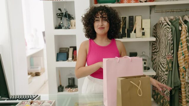 Young middle eastern woman shop assistant smiling confident speaking at clothing store