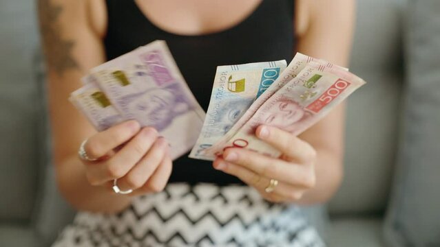 Young woman counting sweden kronor banknotes at home