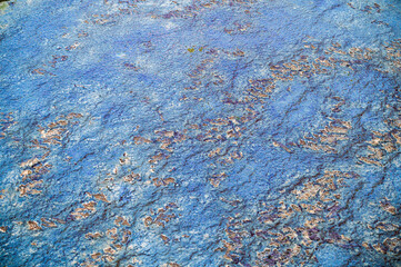 Blue-green oily film of contaminants on the surface of the water