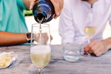 Close-up of man's hand pouring sparkling wine or champagne into the glass