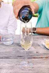 Close-up of man's hand pouring sparkling wine or champagne into the glass