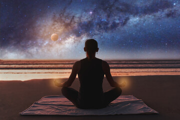 silhouette of a woman on the beach outdoors meditating at night with the moon and milky way in the background