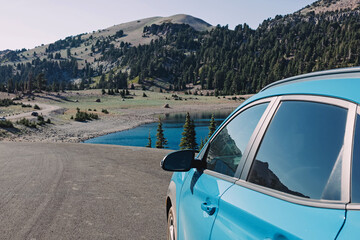 Fototapeta na wymiar Blue car on the the roadside with a view on the mountain lake