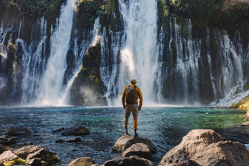 Man traveler looking on the beautiful waterfall