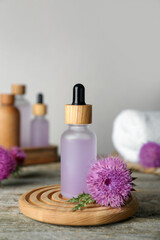 Fototapeta na wymiar Bottle of essential oil and flower on wooden table