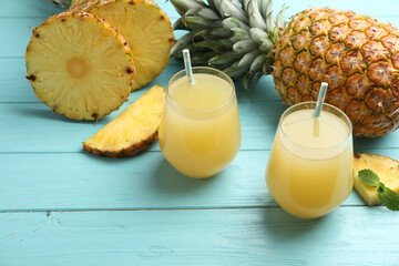 Delicious pineapple juice and fresh fruit on light blue wooden table