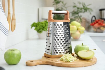Grater and fresh ripe apples on kitchen counter