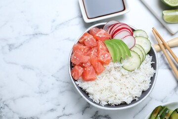 Delicious poke bowl with salmon and vegetables served on white marble table, flat lay. Space for...