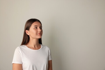 Fototapeta premium Beautiful young woman in white t-shirt on light background. Space for text