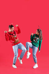 Beautiful happy couple in Santa hats and Christmas sweaters having fun on red background