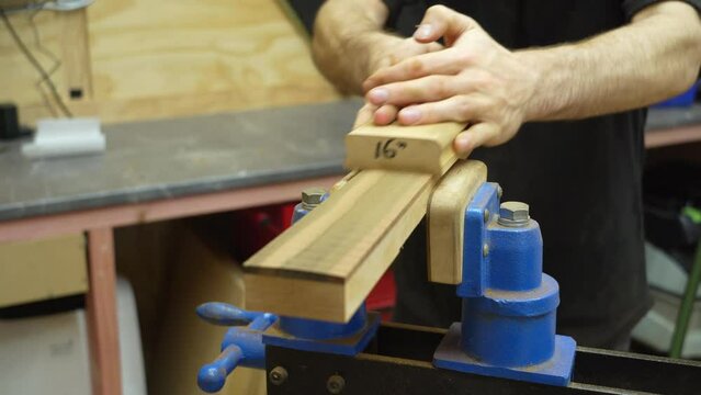 Craftsman roughing in fretboard radius during neck construction of new electric resonator guitar . Close up.