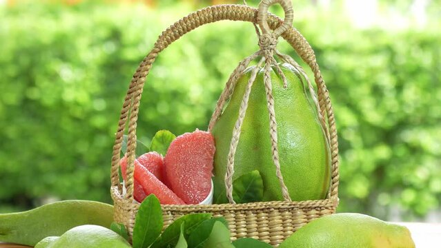 Pomelo fruit in wooden basket on blur garden background, Red Pomelo fruit with slice in wooden basket.