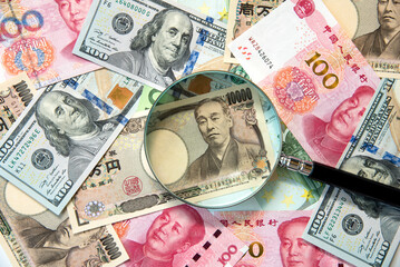 Kkey currency image -US Dollar, JP Yen, Eurp and Chinese Yen with magnifying glass.