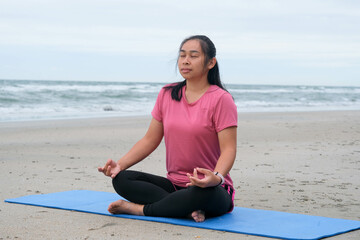 Fototapeta na wymiar Asian woman practicing yoga at seashore. Beautiful woman meditating around the sea beach at sunrise for health. relaxing in nature