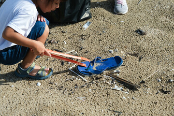 Mother and daughters in gloves cleaning up the beach. Group of young volunteers helping to keep nature clean and picking up the garbage from a sandy shore. Earth day concept