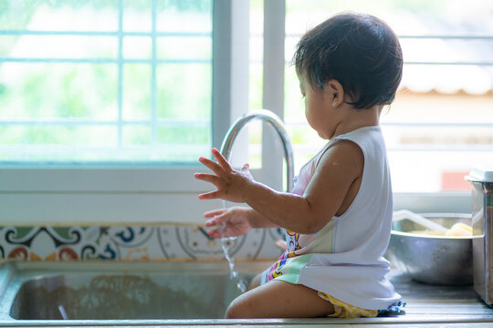 Adorable asian baby girl shower on disk sink enjoying with water