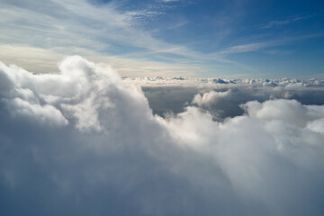 Fototapeta premium Aerial view from airplane window at high altitude of earth covered with puffy cumulus clouds forming before rainstorm