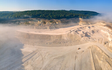 Fototapeta na wymiar Aerial view of open pit mining site of limestone materials extraction for construction industry with excavators and dump trucks