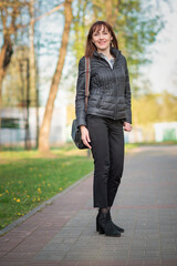 Fototapeta premium Portrait of a young beautiful dark-haired girl in an autumn park.