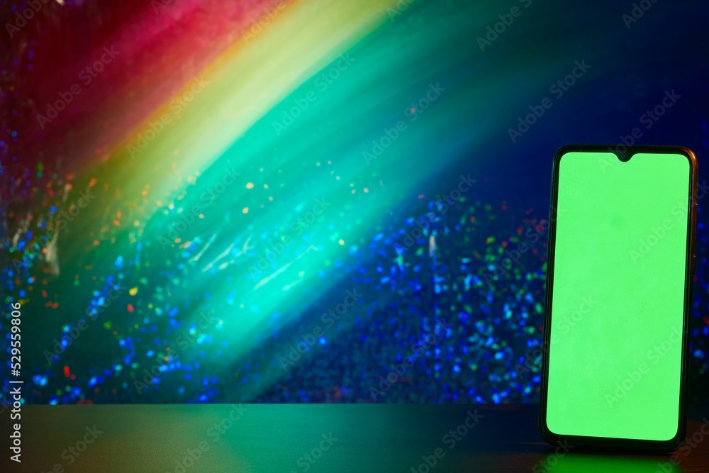 Poster cellular phone with a green screen on a wooden table isolated from a colorful background