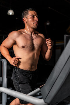 High Quality Photography. Latin Man Running On A Treadmill With A Dark Background. Hispanic Man Training On The Treadmill At The Gym.