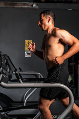 Fototapeta na wymiar High quality photography. Shirtless Hispanic man training on the treadmill. Muscular latin man running in the gym.