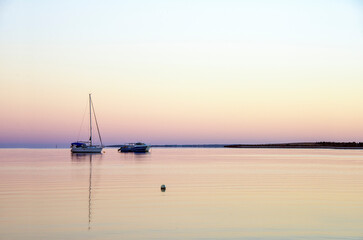 Calm Waters for a fishing boat in the early morning hours against a pastel skyline.