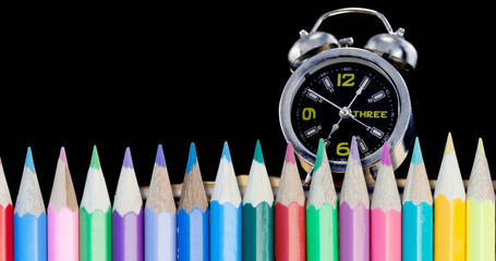 Image of pencils over clock moving on black background
