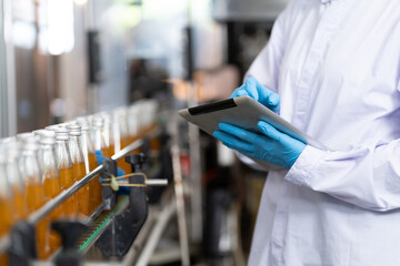 Manufacturer checking product bottles fruit juice on the conveyor belt in the beverage factory....