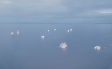 The remains of old wooden piles covered with salt crystals sticking out above the surface of the salt lake Elton