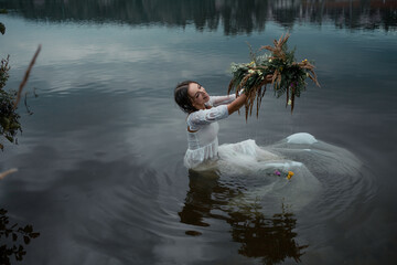 A young woman in the lake holds a wreath over the water. Folk image in the style of the Ivan Kupala holiday