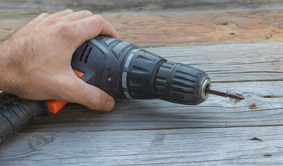 Humand handusing screwdriver on wooden table - From above of crop anonymous person using electric screwdriver while working in workshop