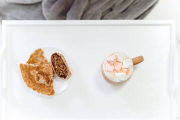 a cup of coffee with marshmallows with breakfast on a white tray on a white background, a feeling of tenderness, morning and security, selective focus