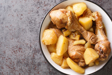 Indonesian semur ayam is a delicious way to prepare chicken and potatoes in a blend of spices, nutmeg, and sweet soy sauce closeup on the bowl on the table. Horizontal top view from above