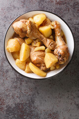 Chicken drumsticks stewed with potatoes in a spicy sweet sauce Indonesian food close-up on the table. Vertical top view from above