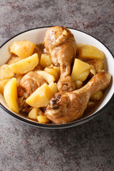 Chicken drumsticks stewed with potatoes in a spicy sweet sauce Indonesian food close-up on the table. Vertical