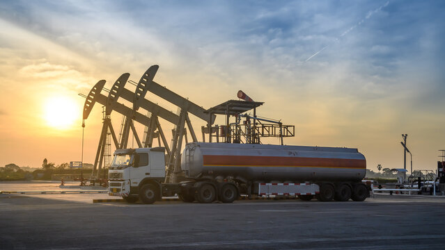Oil field site, in the evening, oil pumps and oil truck