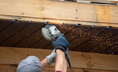 Workers trim the metal roof on the wooden roof
