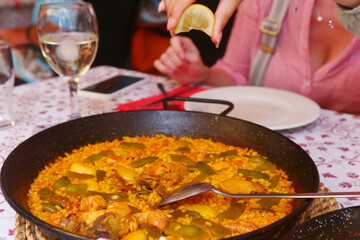 spanish paella close up photo in frying pan with shrimps, peas and lemon slice