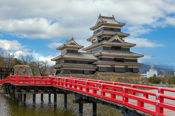Matsumoto Castle (Matsumoto-jo) with Japanese wooden red bridge. Japanese famous historic castles in Nagano Prefecture. Matsumoto castle against blue sky.