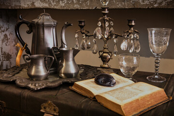 Old magic book with miracle cup and tea pot on vintage iron cabinet. Vintage object decorated as...