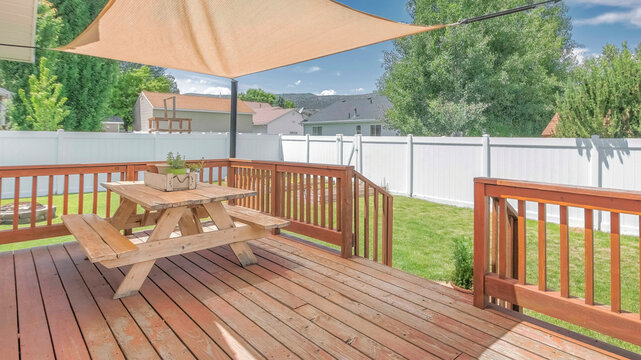 Panorama Whispy white clouds Wooden deck with a sunshade over the table with bench seats