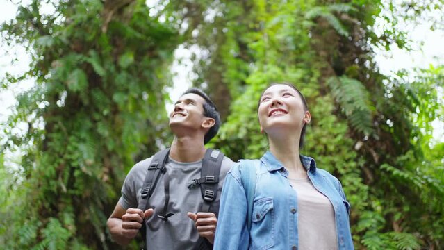 Happy Asian family couple on summer holiday travel vacation trip . Young couple traveler hiking together in tropical forest. Man and woman tourist enjoy outdoor lifestyle trekking in forest mountain.